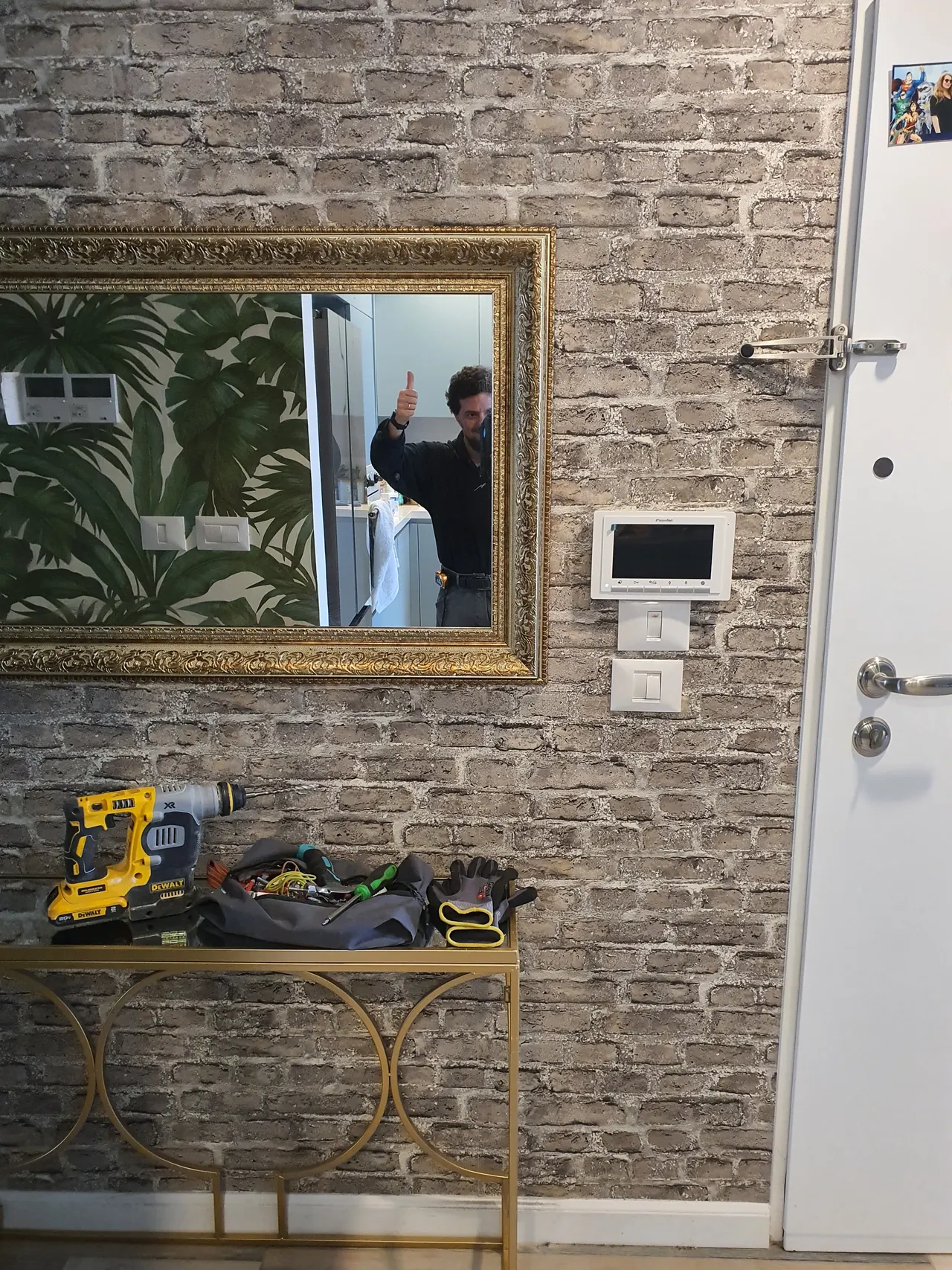 After: large gold-framed mirror hung on a brick-effect hallway wall above a console table
