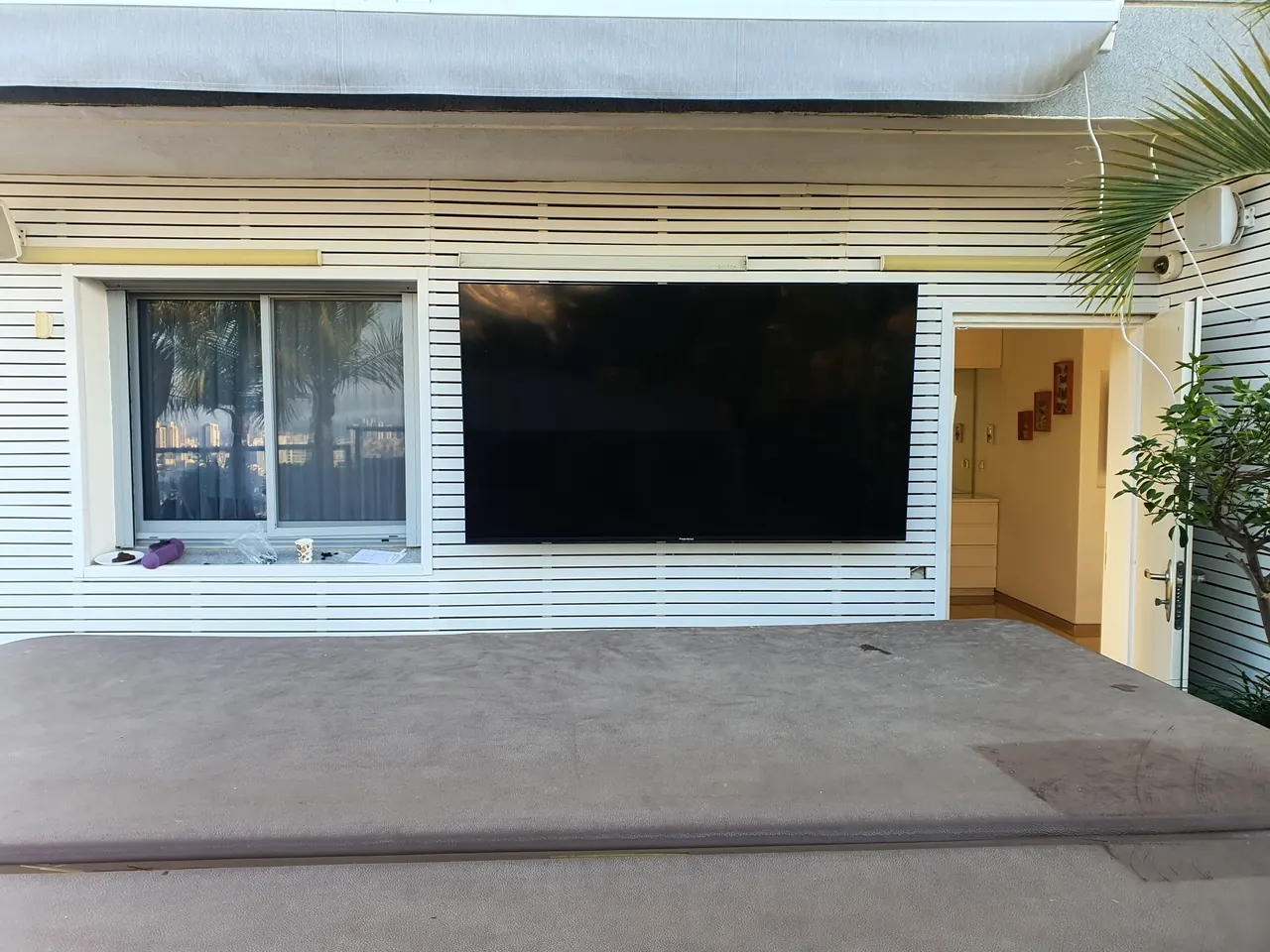 After: large flat-screen TV mounted on an outdoor terrace wall